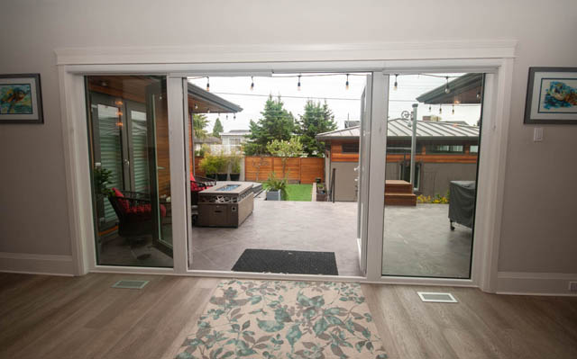 Bright living room with sliding glass doors leading to a private patio and outdoor seating area. - Upper - 876 48th Ave, Vancouver West Side