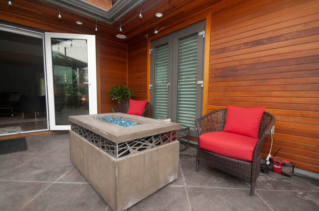 Furnished patio with wooden walls, red cushions, and sliding glass doors. - Upper - 876 48th Ave, Vancouver West Side