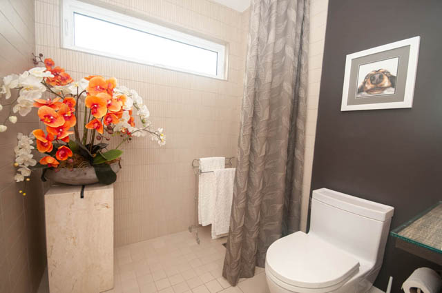 Bathroom with modern decor, orange orchids, and dark walls. - Upper - 876 48th Ave, Vancouver West Side