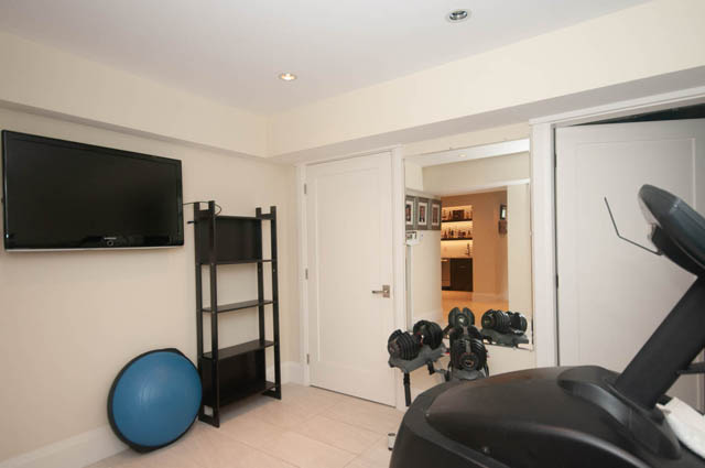 Living room with a flat-screen TV and exercise equipment. - Upper - 876 48th Ave, Vancouver West Side