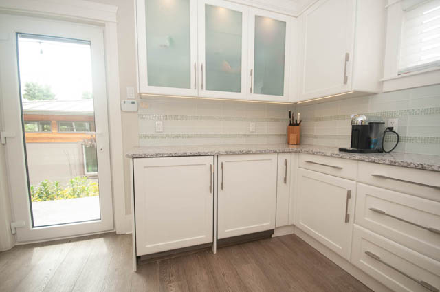 Bright kitchen with white cabinets, granite countertops, and hardwood floors. - Upper - 876 48th Ave, Vancouver West Side