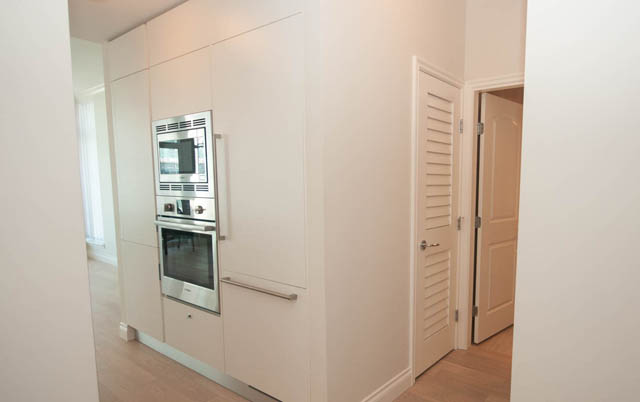 Bright kitchen with white cabinetry and stainless steel appliances, hardwood floors. - 404 - 185 Victory Ship Way, North Vancouver