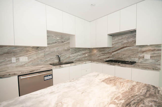Bright kitchen with marble countertops and white cabinetry. - 404 - 185 Victory Ship Way, North Vancouver