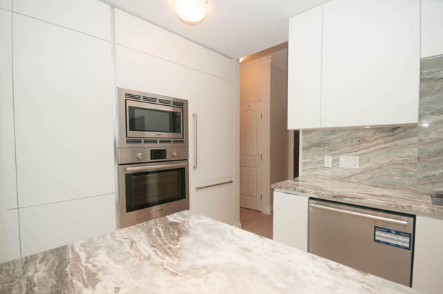 Bright kitchen with white cabinets, stainless steel appliances, and marble countertops. - 404 - 185 Victory Ship Way, North Vancouver