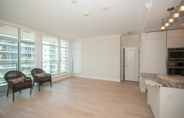 Bright kitchen with granite countertops and hardwood floors, featuring a city view. - 404 - 185 Victory Ship Way, North Vancouver