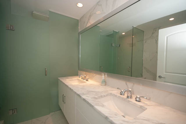 Spacious bathroom with marble countertops and glass shower. - 404 - 185 Victory Ship Way, North Vancouver