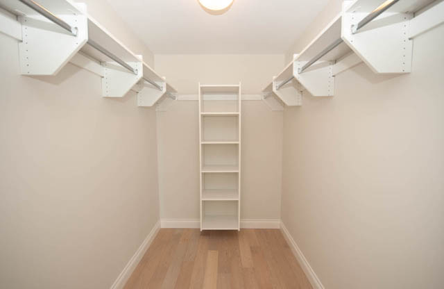 Spacious walk-in closet with wooden flooring and built-in shelving. - 404 - 185 Victory Ship Way, North Vancouver