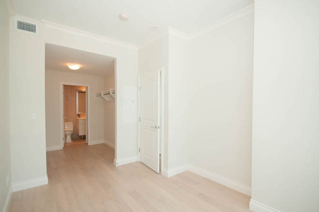 Bright living room with hardwood floors and a view of the hallway. - 404 - 185 Victory Ship Way, North Vancouver