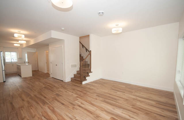 Bright kitchen with white cabinets, hardwood floors, and a staircase leading to the upper level. - 517 E 20th Ave, Vancouver East Side
