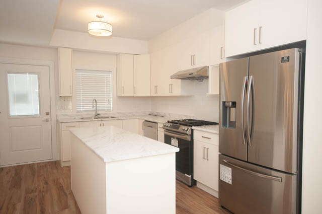 Bright kitchen with white cabinets, marble countertops, and hardwood floors. - 517 E 20th Ave, Vancouver East Side
