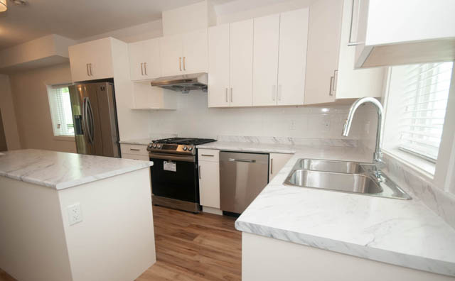 Bright kitchen with white cabinets, marble countertops, and hardwood floors. - 517 E 20th Ave, Vancouver East Side
