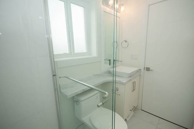 Bright bathroom with white tiles and a large mirror. - 517 E 20th Ave, Vancouver East Side