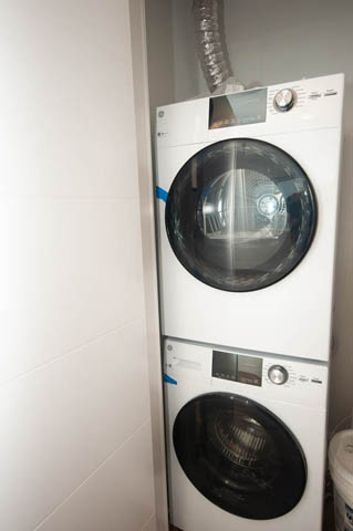 Laundry room with stacked washer and dryer, clean and organized. - 517 E 20th Ave, Vancouver East Side