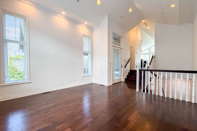 Spacious living room with hardwood floors and large windows overlooking greenery. - 2307 Marine Drive, West Vancouver