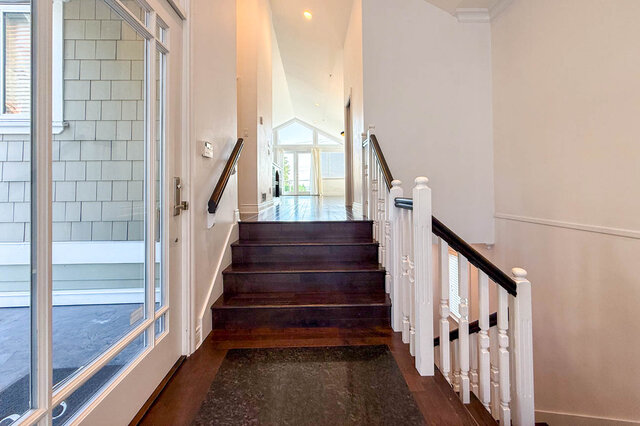 Staircase entryway with dark wood steps and white railings, leading to bright sunlit living area. - 2307 Marine Drive, West Vancouver
