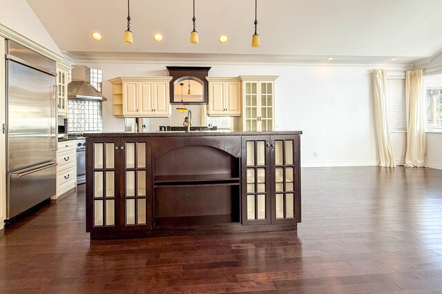 Bright kitchen with dark wood island and glass-front cabinets on rich hardwood floors. - 2307 Marine Drive, West Vancouver