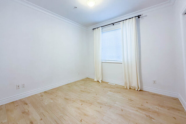 Bright bedroom with light hardwood floors and white curtains. - 2307 Marine Drive, West Vancouver