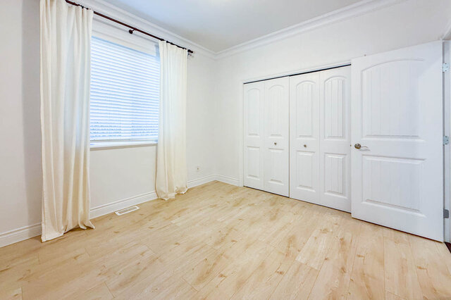 Bright bedroom with light wood flooring and white sliding closet doors. - 2307 Marine Drive, West Vancouver