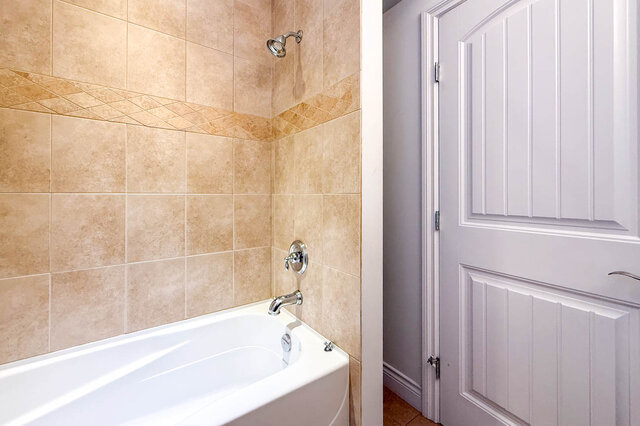 Bathroom with beige tile walls and decorative border, white bathtub. - 2307 Marine Drive, West Vancouver
