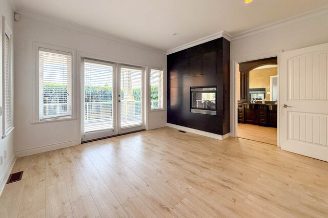 Spacious living room with light hardwood floors and large windows overlooking greenery. - 2307 Marine Drive, West Vancouver