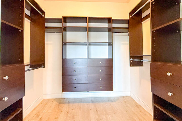 Walk-in closet with dark wood cabinetry and light hardwood floors. - 2307 Marine Drive, West Vancouver