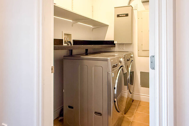 Laundry room with stainless steel washer/dryer and black countertop. - 2307 Marine Drive, West Vancouver