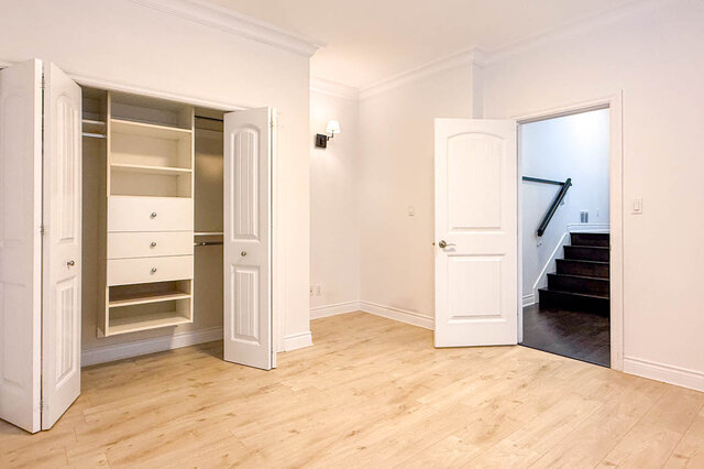 Spacious bedroom with built-in closet shelves and light hardwood floors. - 2307 Marine Drive, West Vancouver