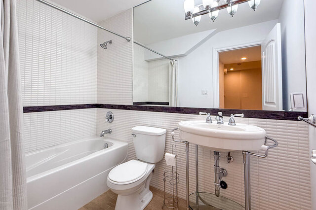 Bright bathroom with white tile walls and chrome fixtures. - 2307 Marine Drive, West Vancouver
