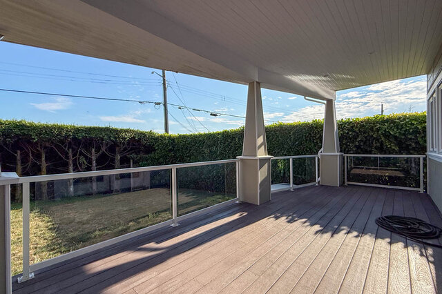 Covered deck with wooden flooring and lush green hedge views. - 2307 Marine Drive, West Vancouver