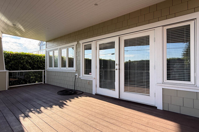 Covered deck with hardwood flooring and white-framed sliding glass doors. - 2307 Marine Drive, West Vancouver