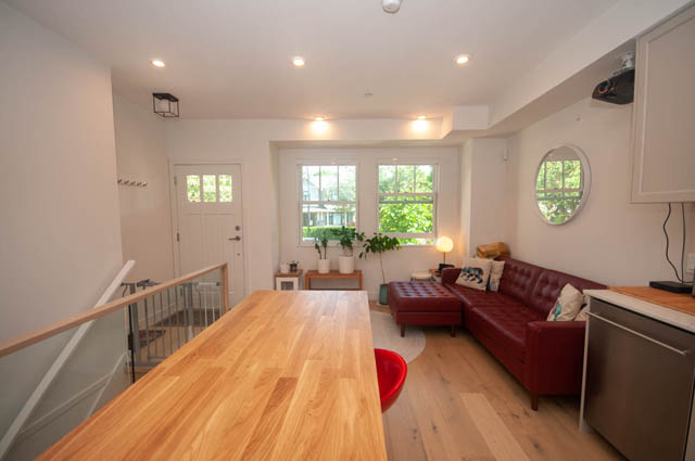 Furnished living room with hardwood floors and a cozy red sofa. - 114 West 14th Ave, Vancouver West Side
