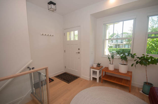 Bright entryway with wooden floors, plants, and a city view. - 114 West 14th Ave, Vancouver West Side