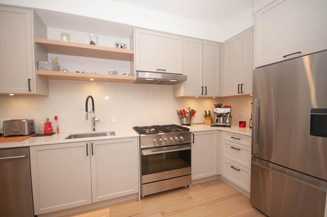 Bright kitchen with white cabinets, stainless steel appliances, and wooden countertops. - 114 West 14th Ave, Vancouver West Side
