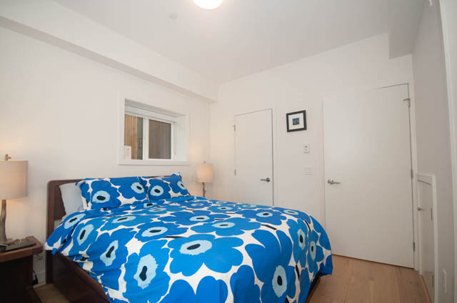 Bright bedroom with blue floral bedding and white walls. - 114 West 14th Ave, Vancouver West Side