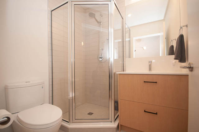 Bright bathroom with wooden cabinets and modern shower. - 114 West 14th Ave, Vancouver West Side