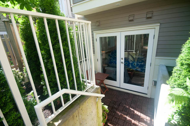 Bright patio with white railing and lush greenery, leading to a cozy outdoor space. - 114 West 14th Ave, Vancouver West Side