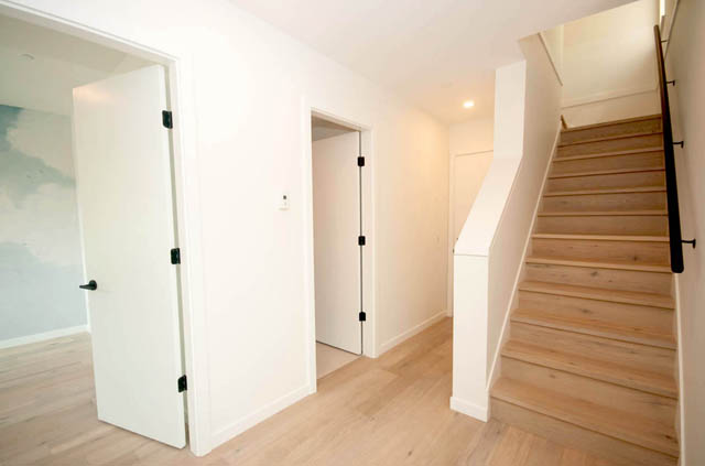 Bright hallway with white walls, wooden stairs, and hardwood floors. - 9 - 528 East 2nd, North Vancouver