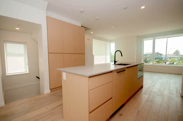 Bright kitchen with light wood cabinets, white countertops, and a city view. - 9 - 528 East 2nd, North Vancouver