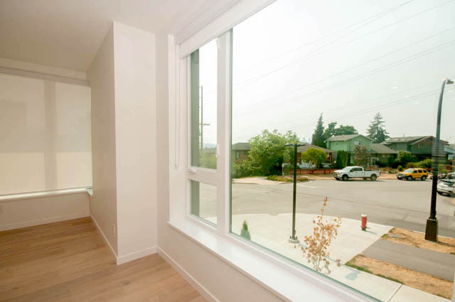 Bright living room with large windows, hardwood floors, and a view of the city. - 9 - 528 East 2nd, North Vancouver