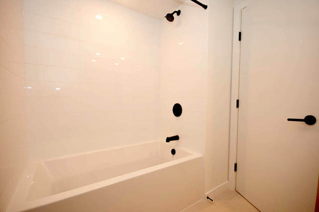 Spacious bathroom with white tiles and modern black fixtures. - 9 - 528 East 2nd, North Vancouver
