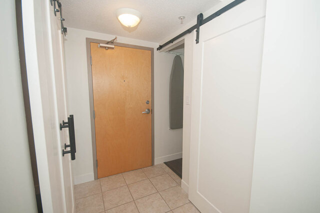 Entryway with sliding barn door and tiled flooring, leading to a cozy 1-bedroom + den condo. - 1907 - 1420 West Georgia Street, Vancouver Downtown
