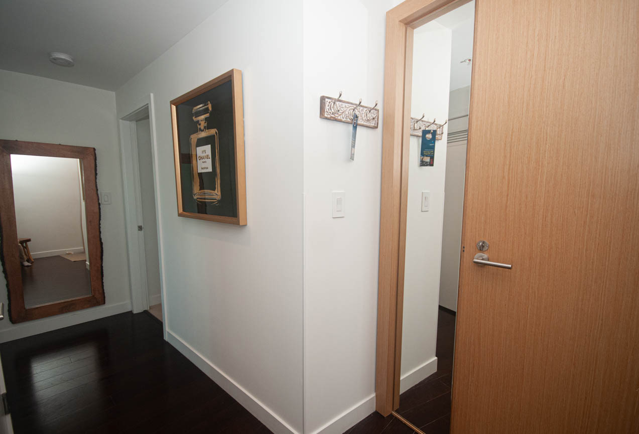 Bright hallway with dark hardwood floors and a framed Chanel perfume bottle artwork. - 4502 - 777 Richards St, Vancouver Downtown