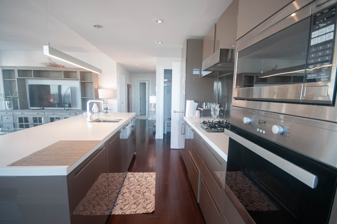 Bright kitchen with modern appliances, dark wood floors, and a large island. - 4502 - 777 Richards St, Vancouver Downtown