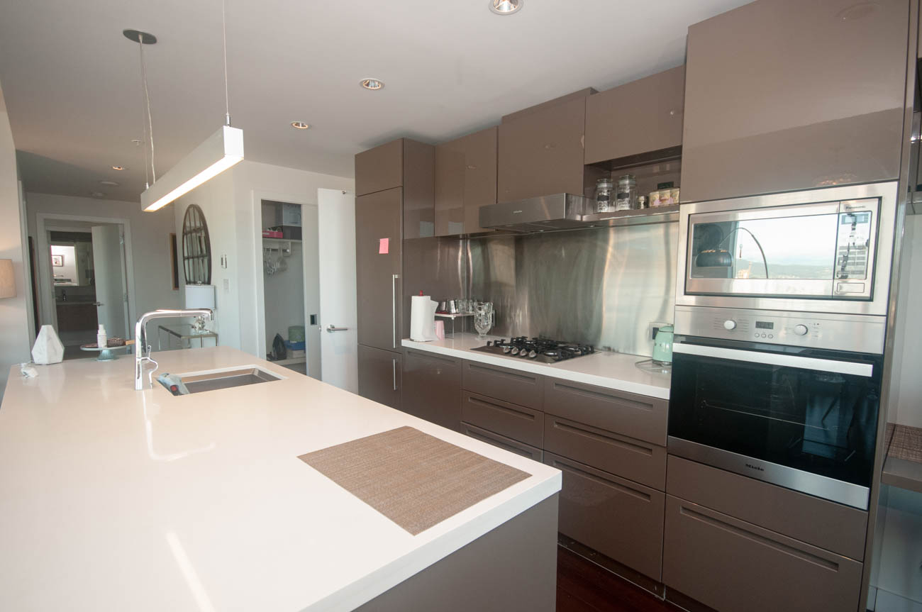 Bright kitchen with white countertops, stainless steel appliances, and a city view. - 4502 - 777 Richards St, Vancouver Downtown