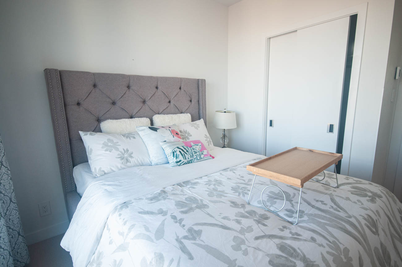 Furnished bedroom with tufted headboard and floral bedding. - 4502 - 777 Richards St, Vancouver Downtown