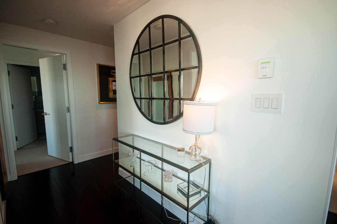 Bright entryway with glass-topped console table, round mirror, and modern lighting. - 4502 - 777 Richards St, Vancouver Downtown