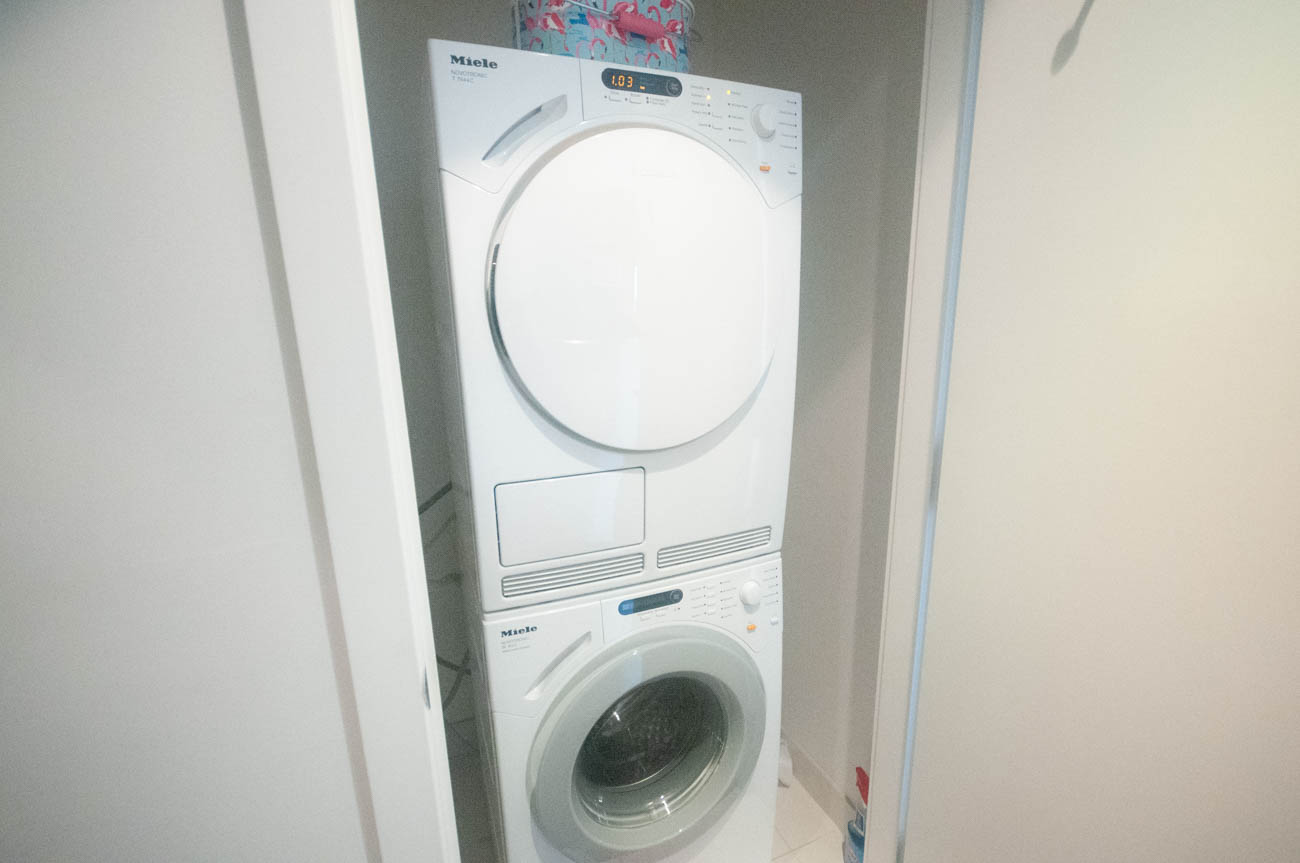 Bright laundry room with stacked Miele washer and dryer, white walls. - 4502 - 777 Richards St, Vancouver Downtown