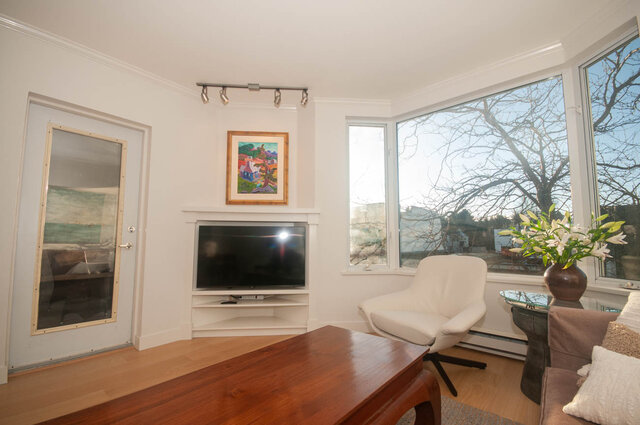 Spacious living room with hardwood floors, large bay window, and a modern fireplace. - 308 - 1688 Cypress Street, Vancouver West Side