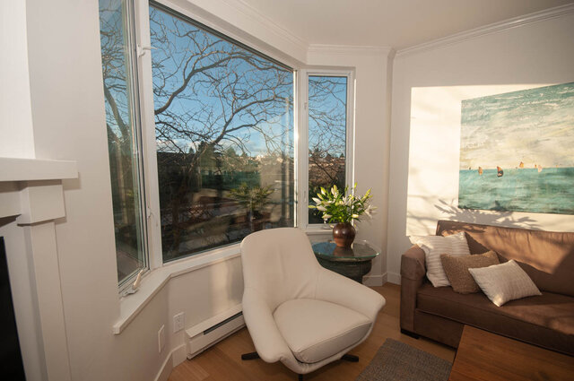 Bright living room with large bay window, hardwood floors, and a cozy corner sofa. - 308 - 1688 Cypress Street, Vancouver West Side