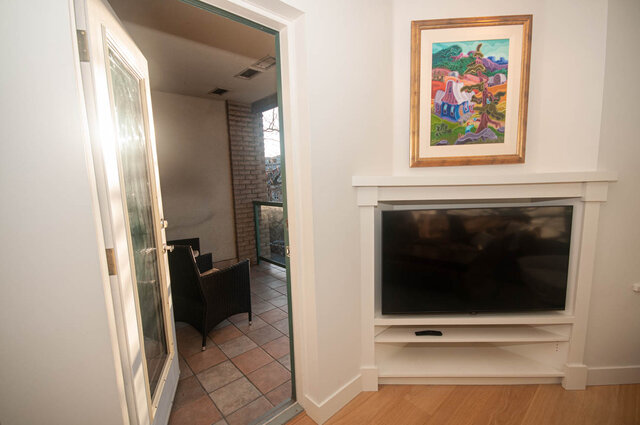 Spacious living room with hardwood floors, a fireplace, and a view of the city through the sliding glass door.